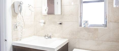 A modern bathroom with a white sink, dark wooden cabinets, a white toilet, and a window with a towel rack.