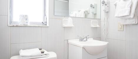 A modern bathroom with a toilet, sink, mirror, and window.