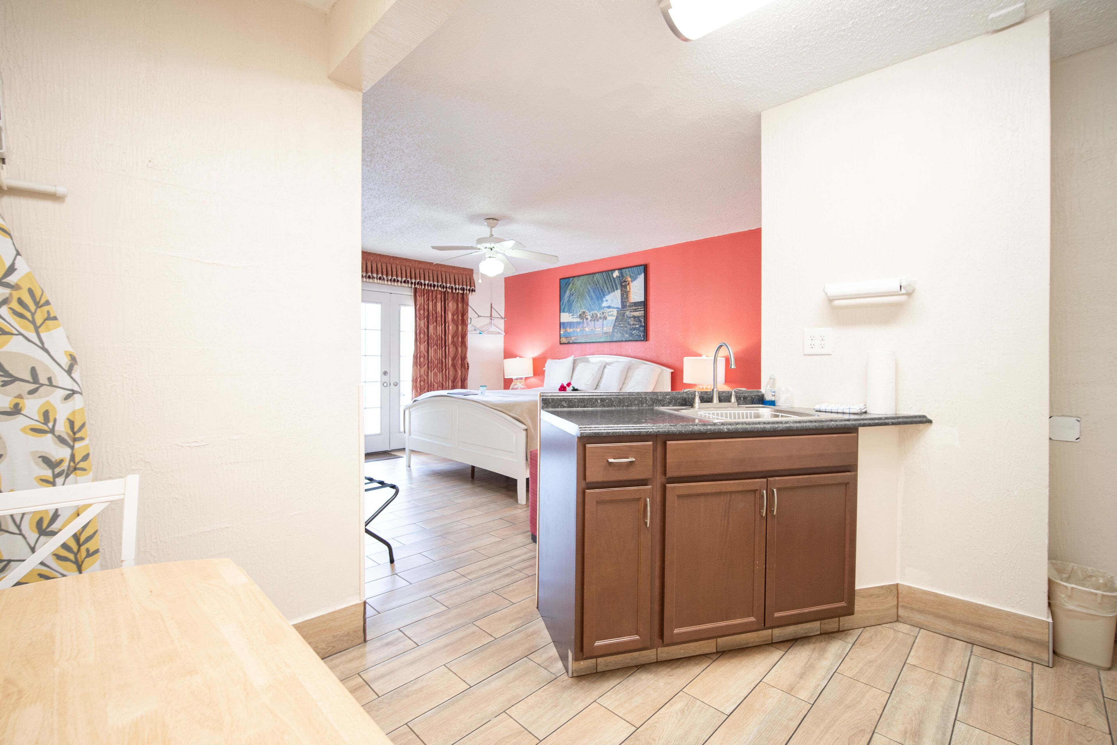 Une chambre d’hôtel de taille réduite, dotée d’une kitchenette, d’un lit et d’une salle de bain.