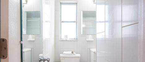 Un bagno stretto con due servizi igienici, una finestra e uno specchio.
