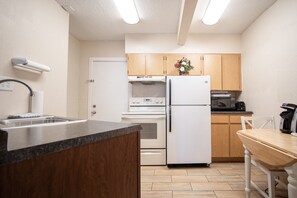 Una cocina compacta con armarios de madera, un refrigerador blanco, una estufa y un microondas.