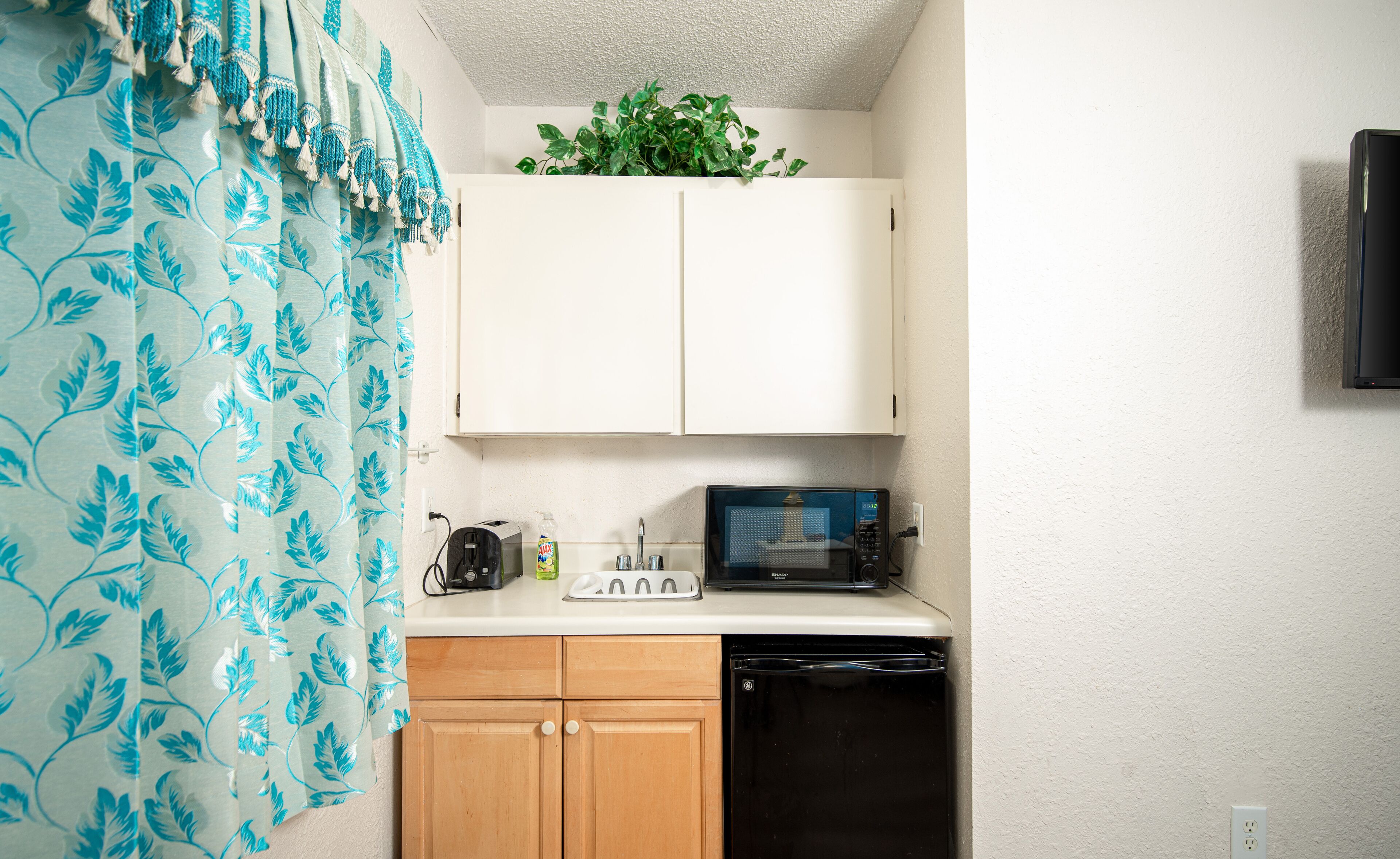 A compact kitchen with a microwave, toaster, and a small refrigerator.