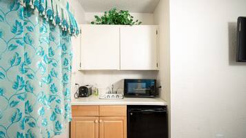 A compact kitchen with a microwave, toaster, and a small refrigerator.