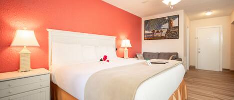 Habitación de hotel con cama, mesitas de noche, ventilador de techo y un cuadro en la pared.