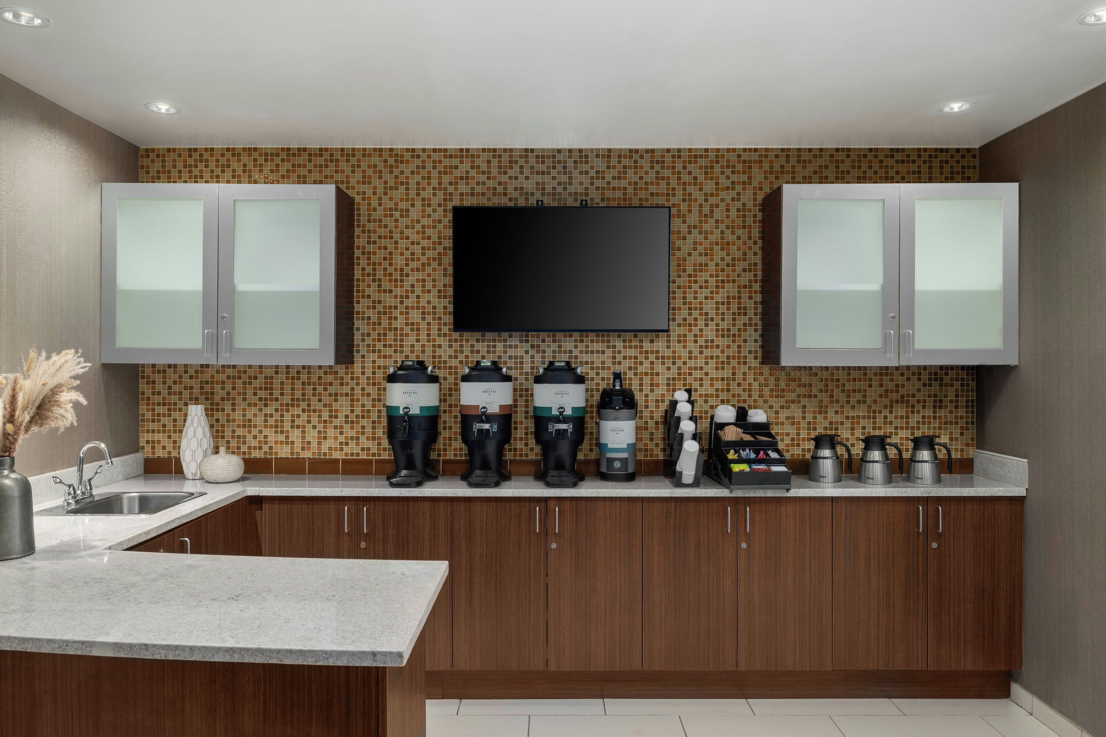 A modern kitchen with a tiled backsplash, stainless steel appliances, and wooden cabinets.