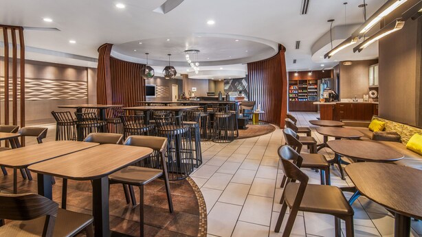 Un restaurante moderno con mesas redondas, taburetes altos y una zona de bar central.