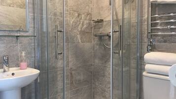 A modern bathroom with a glass-enclosed shower, a white sink, and a toilet.