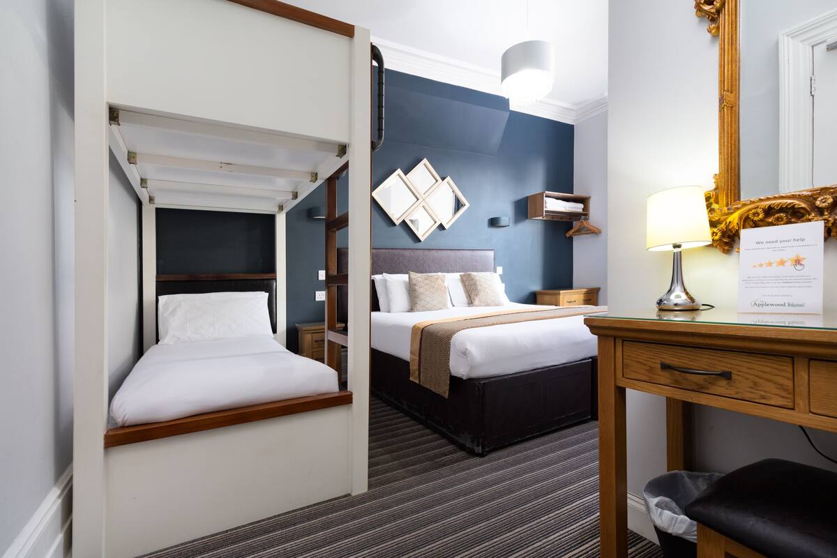 A hotel room with a bed, a desk, and a mirror.