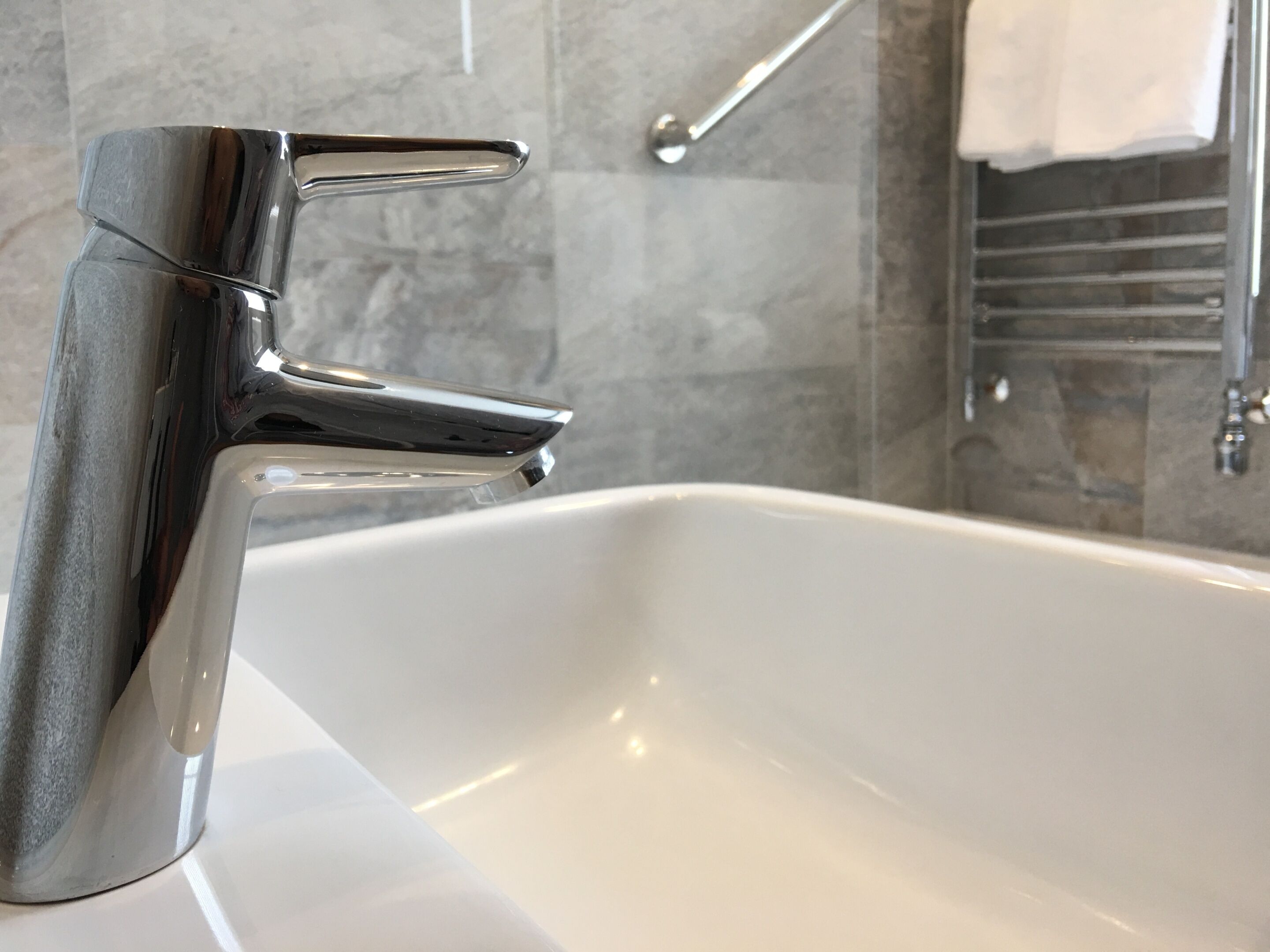 Un baño moderno con un grifo cromado, un lavabo blanco y un perchero en la pared.