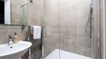 A modern bathroom with a glass shower enclosure, a white sink, and a mirror above it.