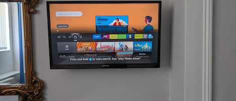 Ein an der Wand befestigter Fernseher zeigt eine Streaming-Oberfläche mit verschiedenen Inhalten.