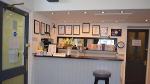 A reception area with a counter, framed certificates, a clock, and a 'No Entry' sign. - The Cameo (Blackpool)
