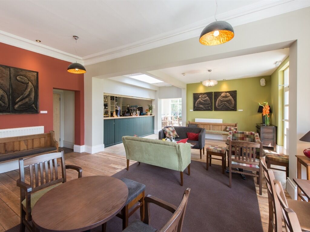 A spacious living area with a dining table, sofas, and a kitchen in the background.