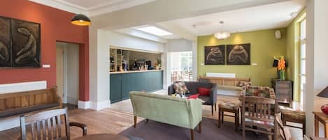 A spacious living area with a dining table, sofas, and a kitchen in the background.
