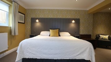 A large bed with a white bedspread and two pillows, a dark headboard, and two wall-mounted lights.