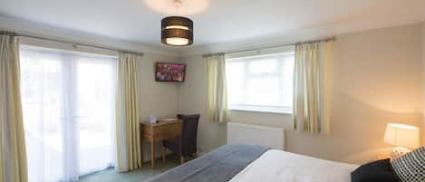 A hotel room with a bed, desk, chair, and a television on the wall.