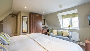 A bedroom with a large bed, a desk, a sofa, and a window with a view.