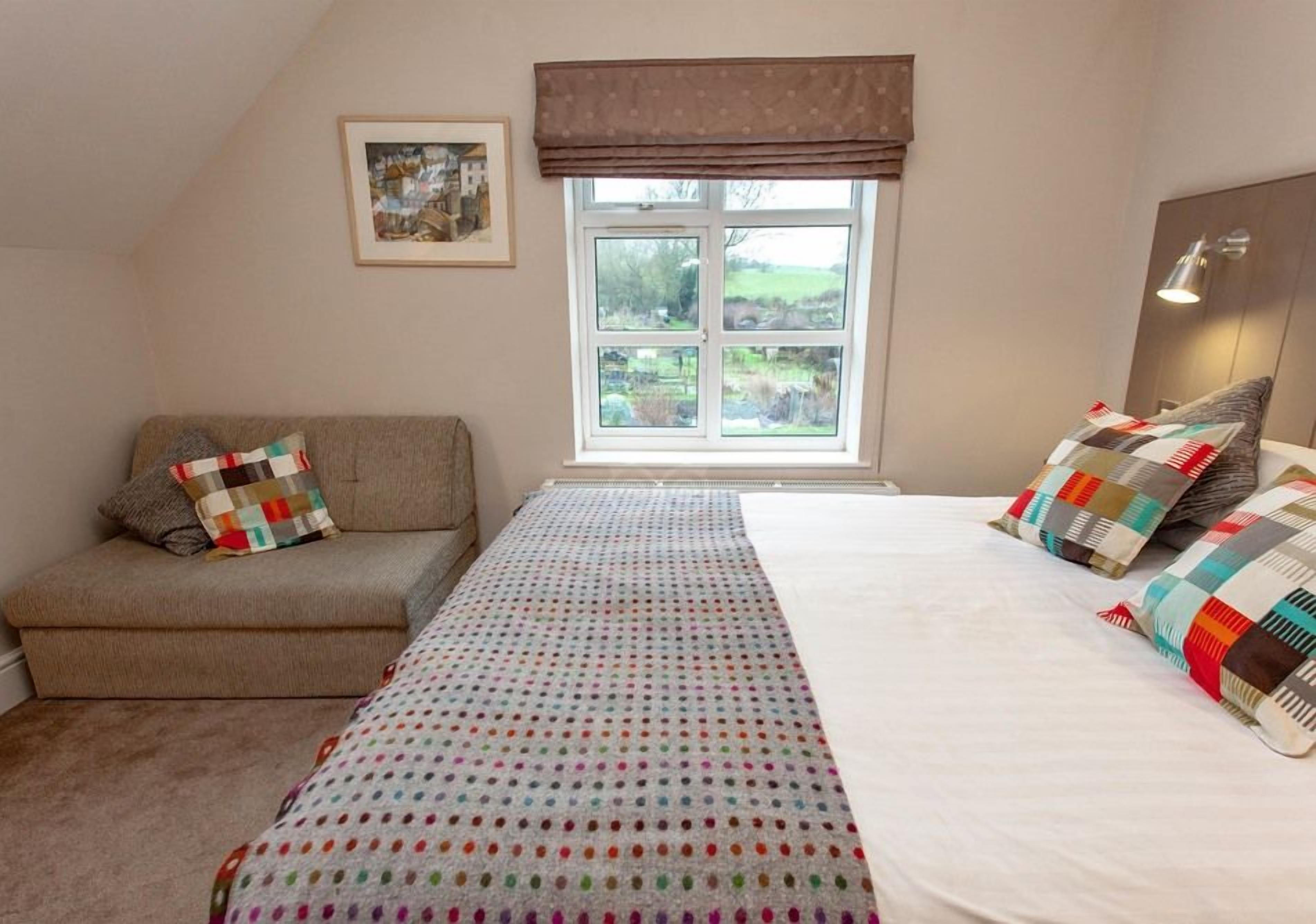 A bedroom with a bed, a sofa, a window, and a radiator.