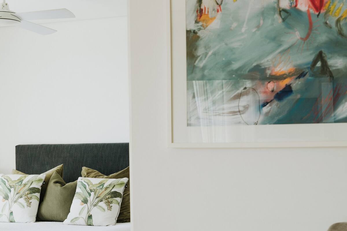 A bedroom with a bed, a chair, and a painting on the wall.