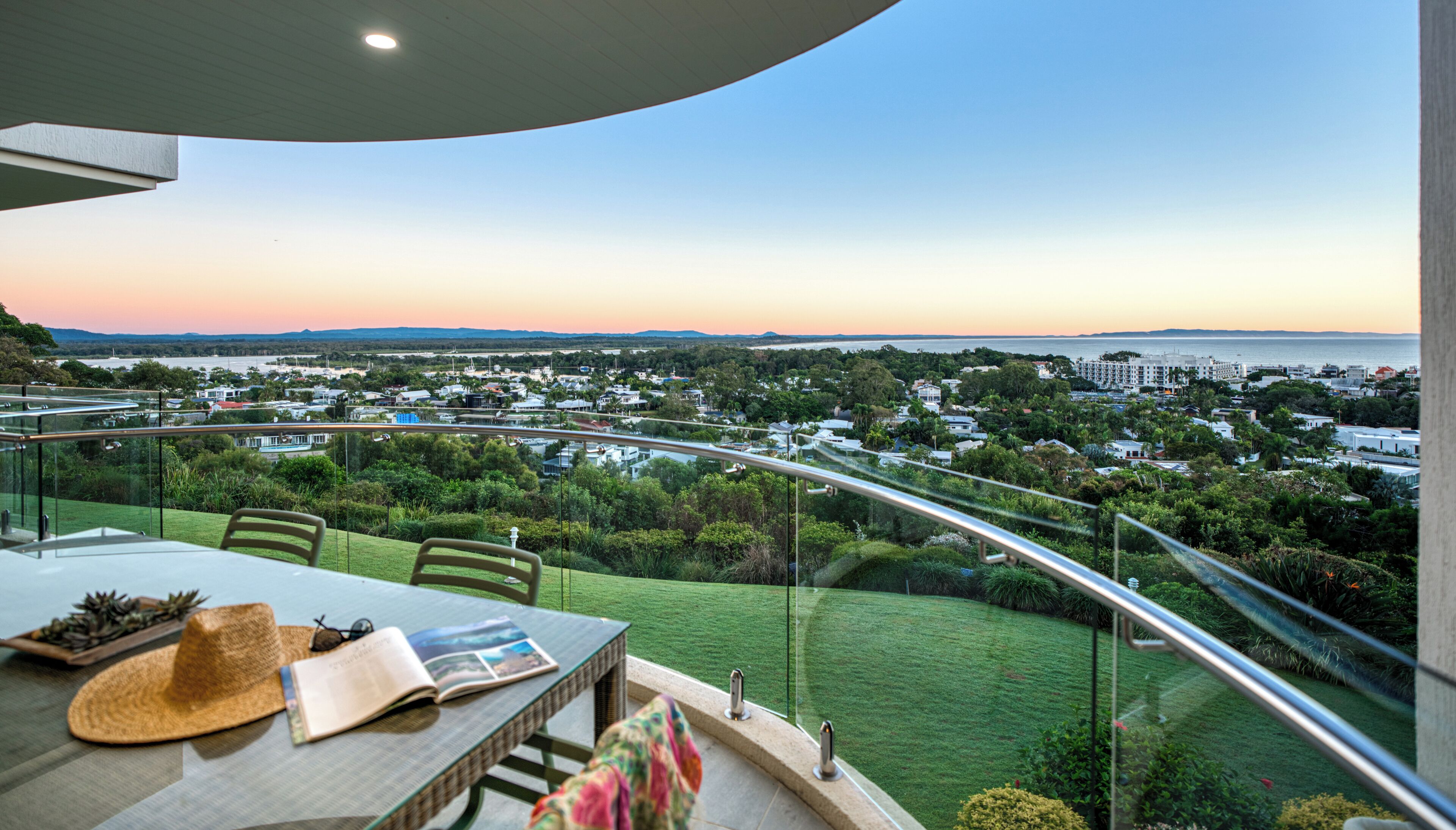 A balcony with a view of a coastal town at sunset.