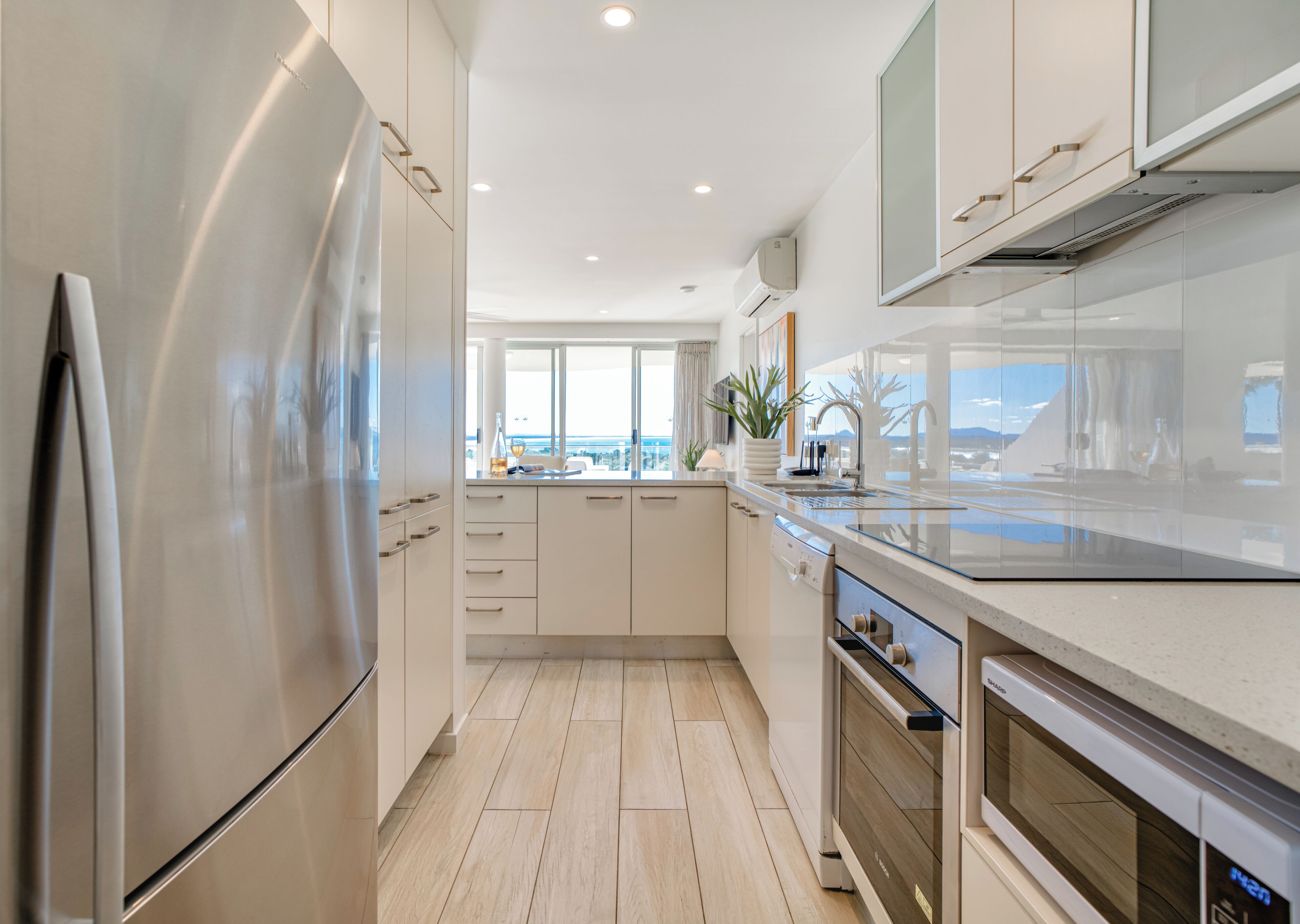 A modern kitchen with stainless steel appliances, white cabinetry, and a view of the city.