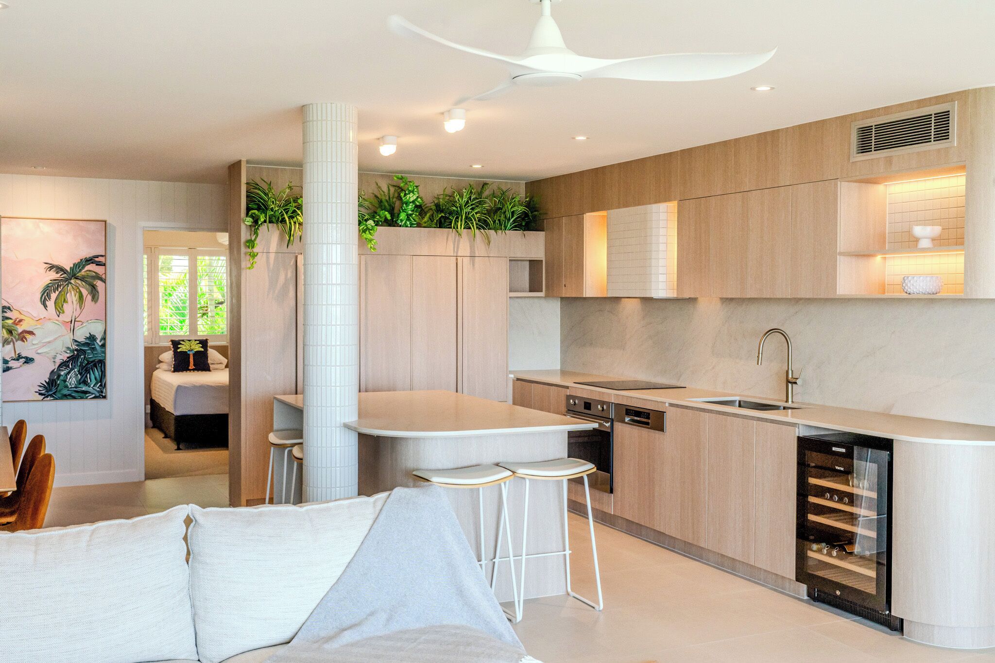 A modern kitchen with a central island, bar stools, and a built-in dishwasher.