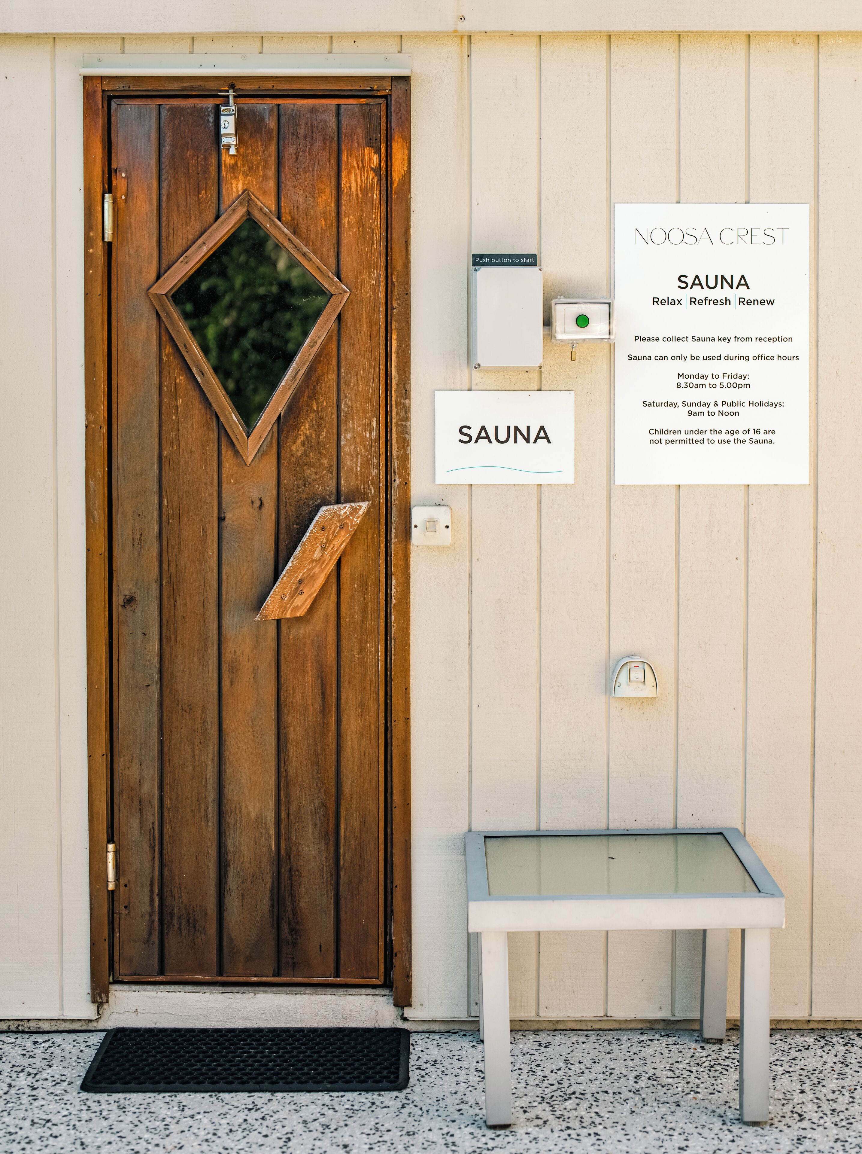 A wooden door with a sign indicating a sauna, a push button, and a key collection point.