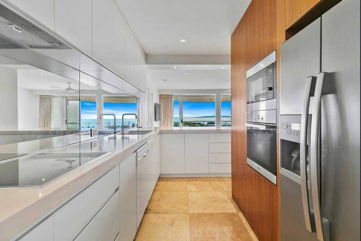 A modern kitchen with stainless steel appliances, a large island, and a view of the ocean.