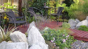 A garden patio with stone seating, a small table, and chairs. - Sherborne Motor Lodge (Christchurch)