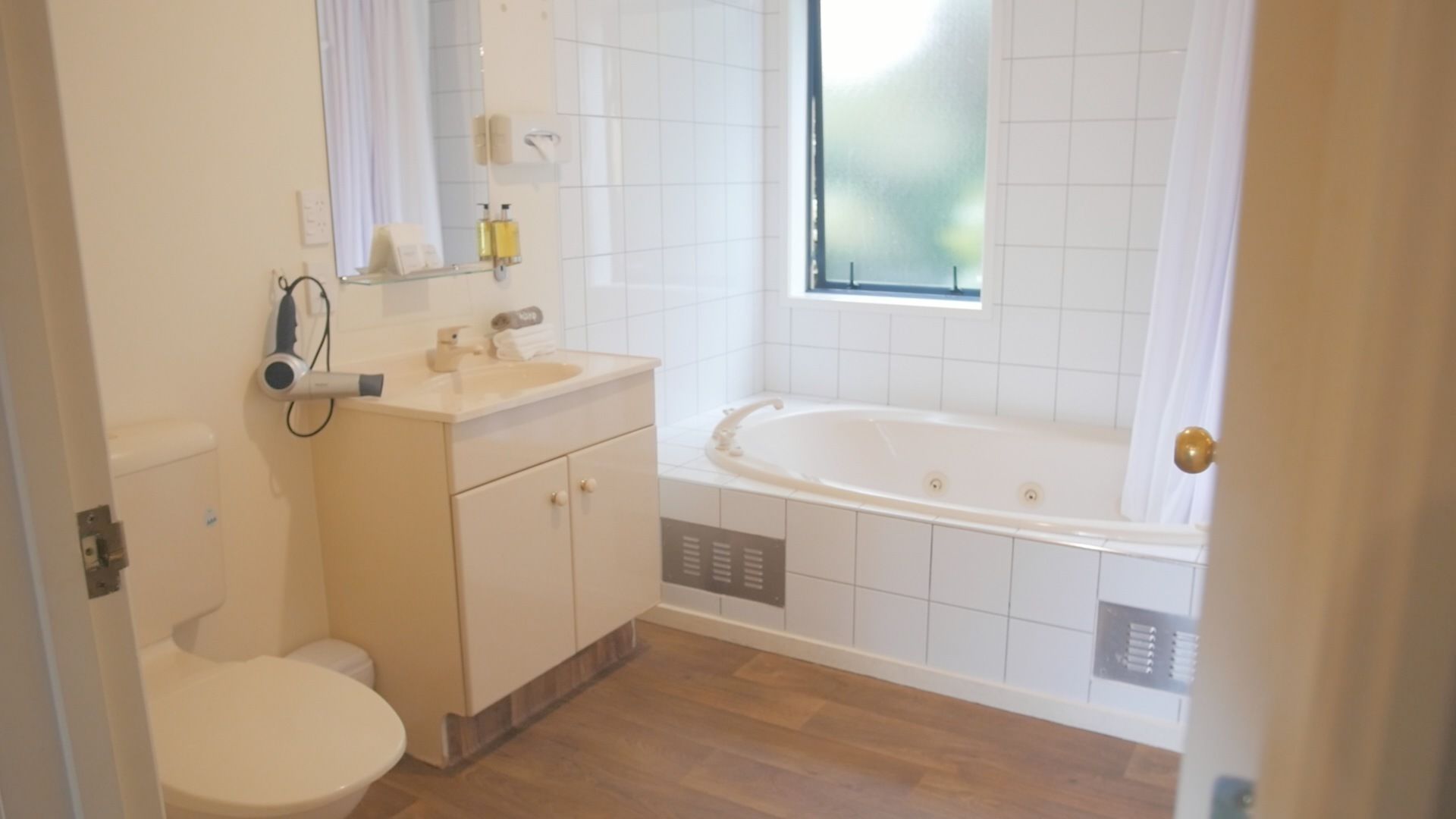 A bathroom with a toilet, sink, mirror, and bathtub.