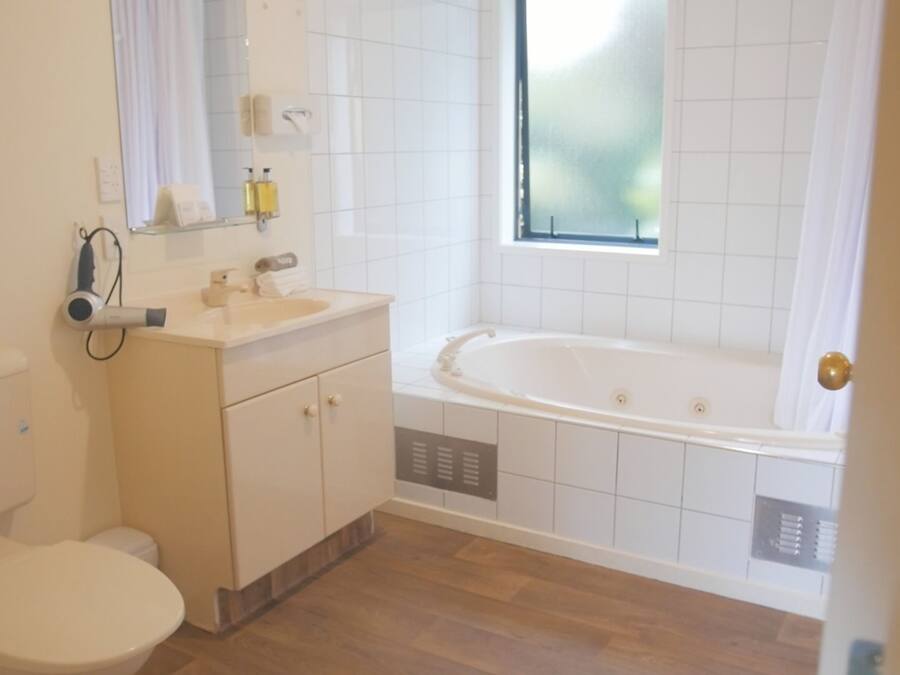 A bathroom with a toilet, sink, mirror, and bathtub.