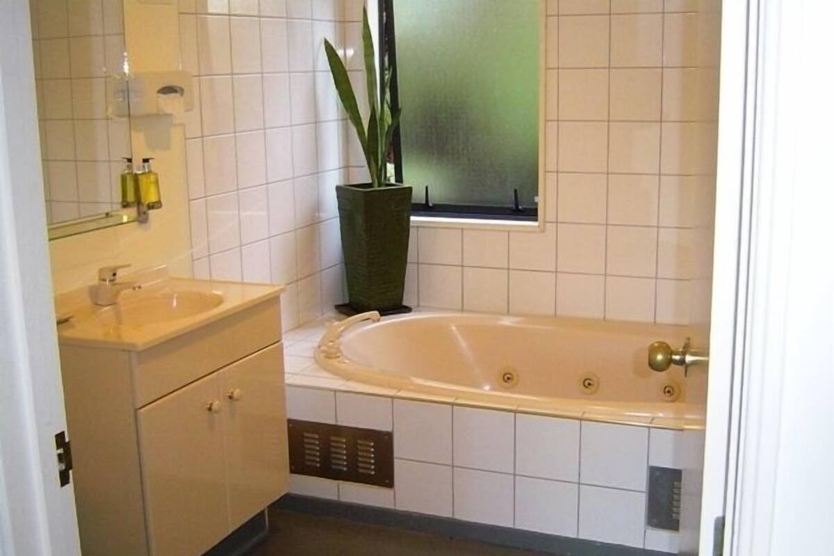 A bathroom with a bathtub, a sink, and a mirror.