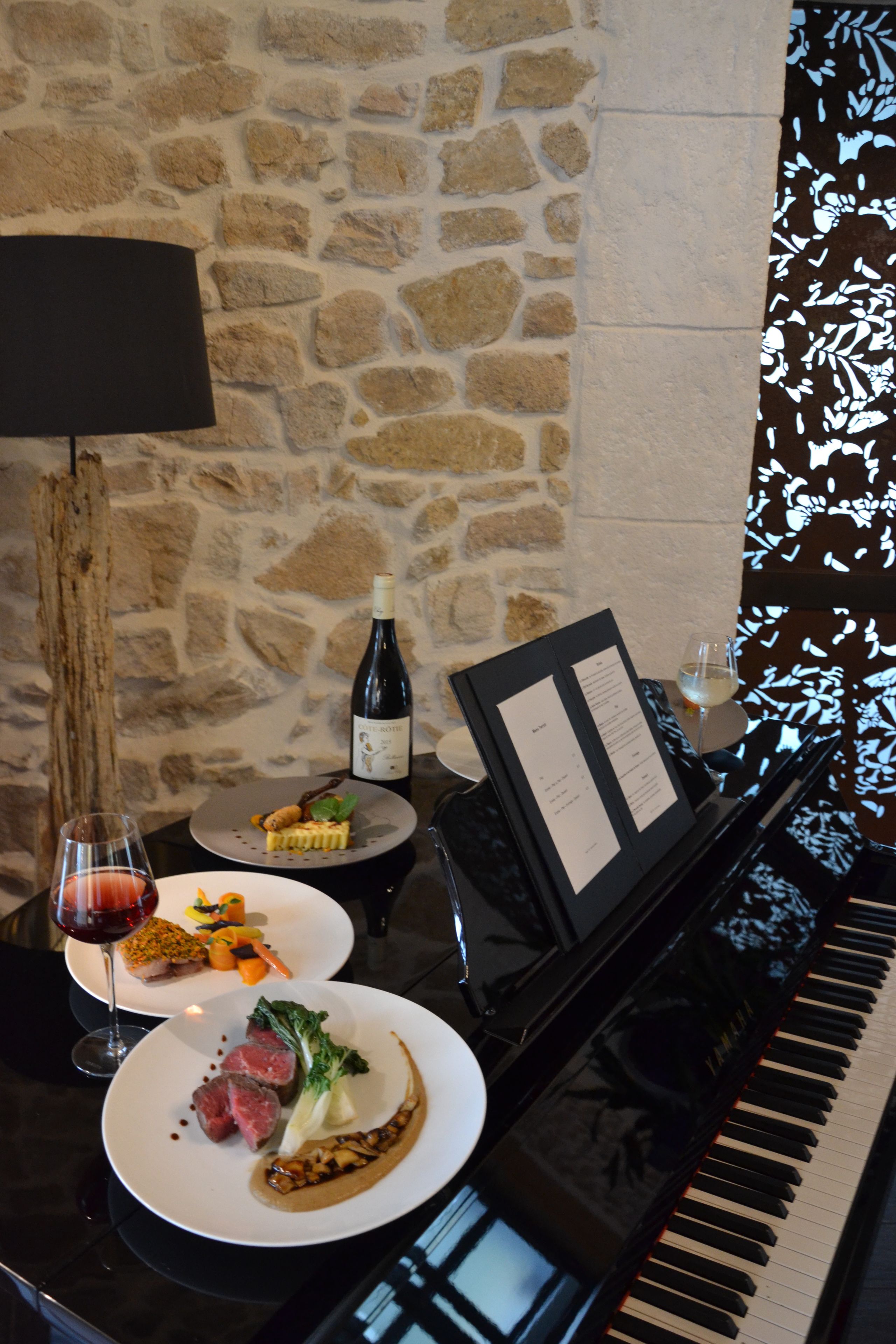 A dining table with plates of food, a bottle of wine, and a menu.