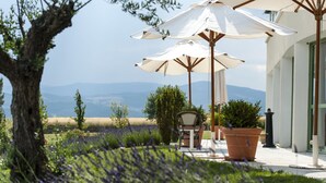 Un patio con mobiliario exterior, sombrillas y vistas al paisaje.