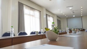 Een vergaderruimte met een lange tafel, stoelen, waterflesjes en een plant.