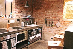 Una cocina con pared de ladrillo, electrodomésticos de acero inoxidable y taburetes de madera.