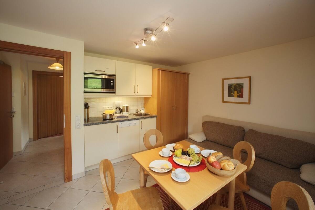 A compact living space with a kitchenette, dining area, and a sofa.