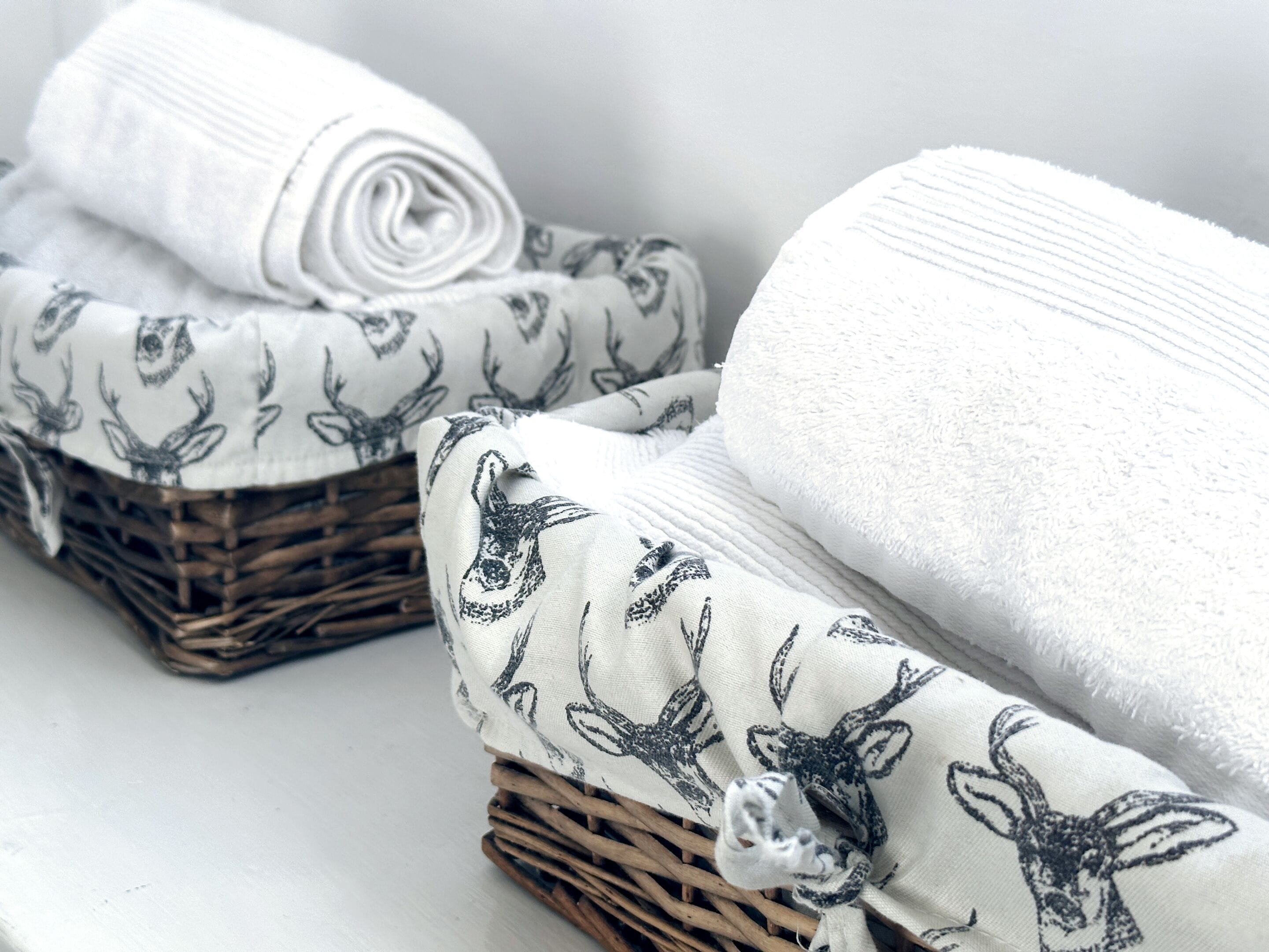 A set of neatly folded towels with deer patterns, placed on a white surface.