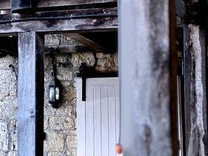 A rustic stone wall with a wooden door and a hanging light fixture. - The Crown at Marnhull (Sturminster Newton)