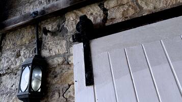 A stone wall with a wooden beam and a white door with black trim.