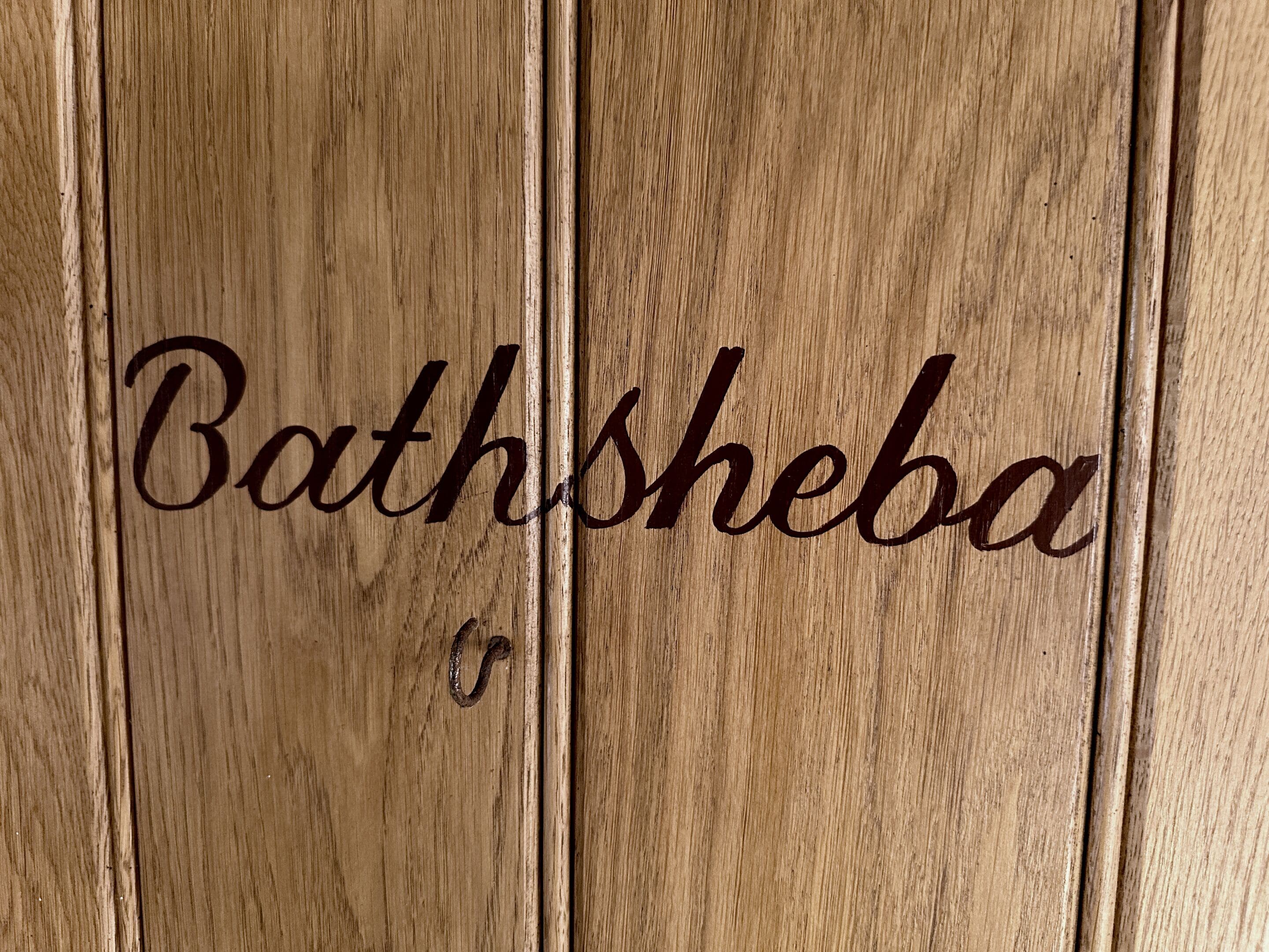 Una superficie de madera con el texto "Bathsheba" y un pequeño gancho.