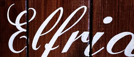 Una superficie de madera con la palabra "Elleria" escrita con caligrafía.