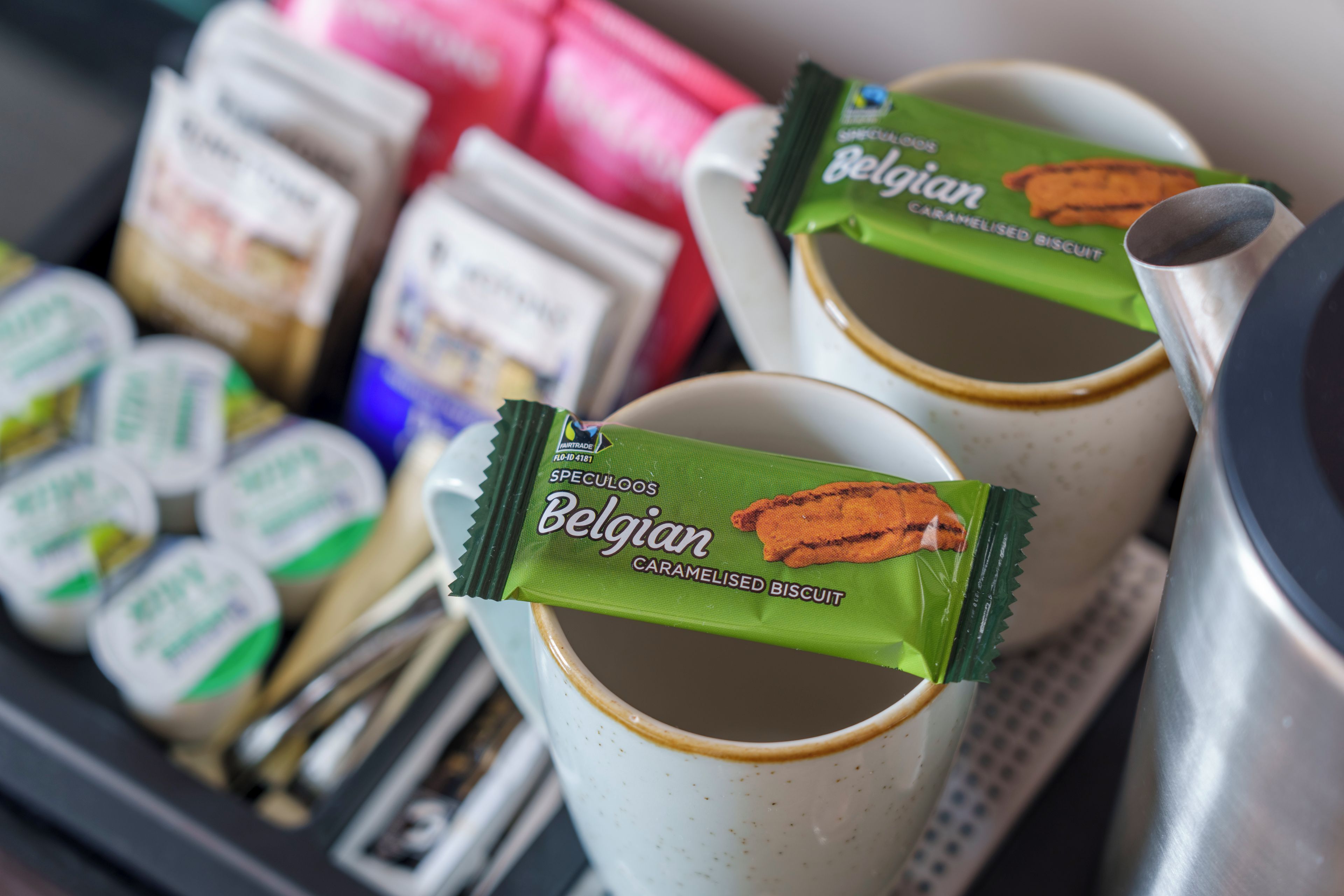 A tray with several cups and packets of Belgian caramels.