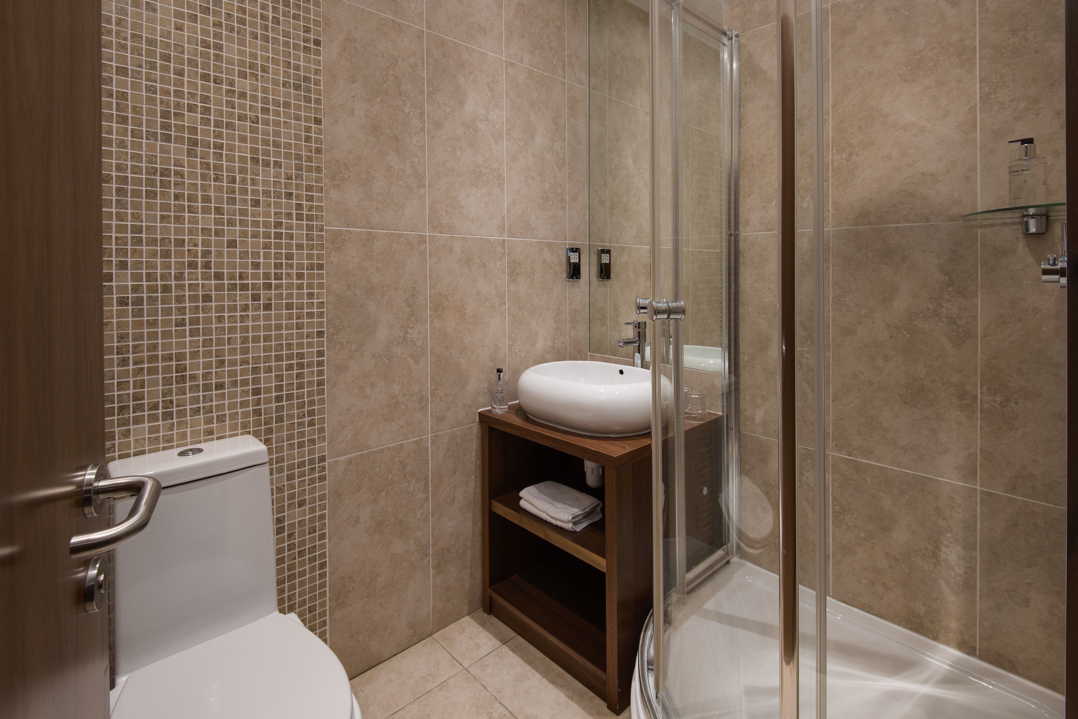 Une salle de bain équipée de toilettes, d’un lavabo et d’une douche à parois en verre.