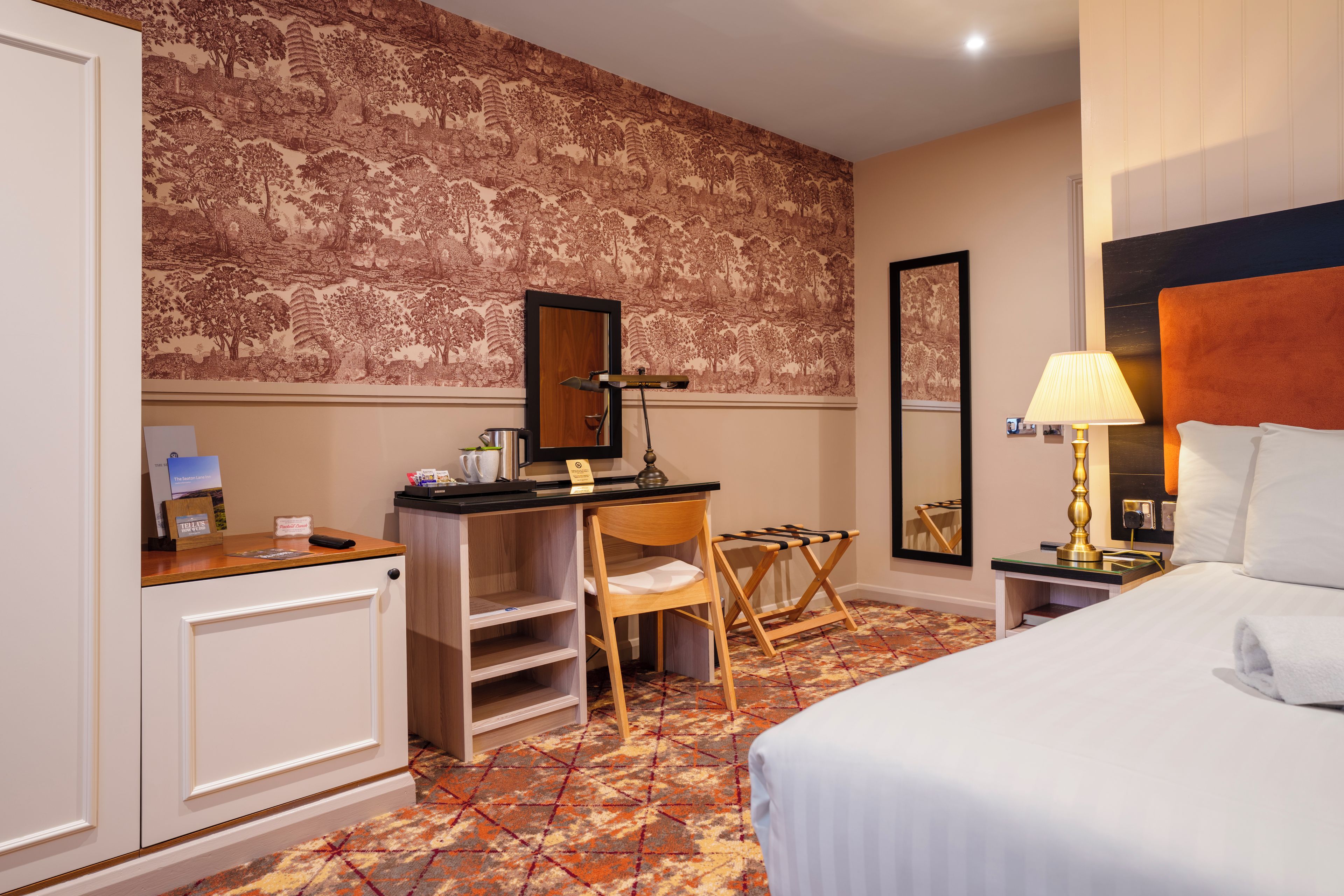Una habitación de hotel con cama, escritorio, silla y un espejo grande.