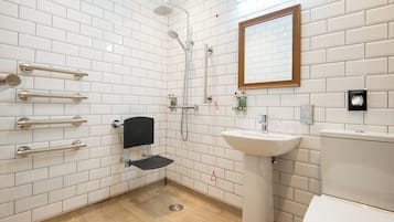 Een moderne badkamer met witte metrotegels, een spiegel met houten lijst, een witte wastafel en een douche met een handdouche.