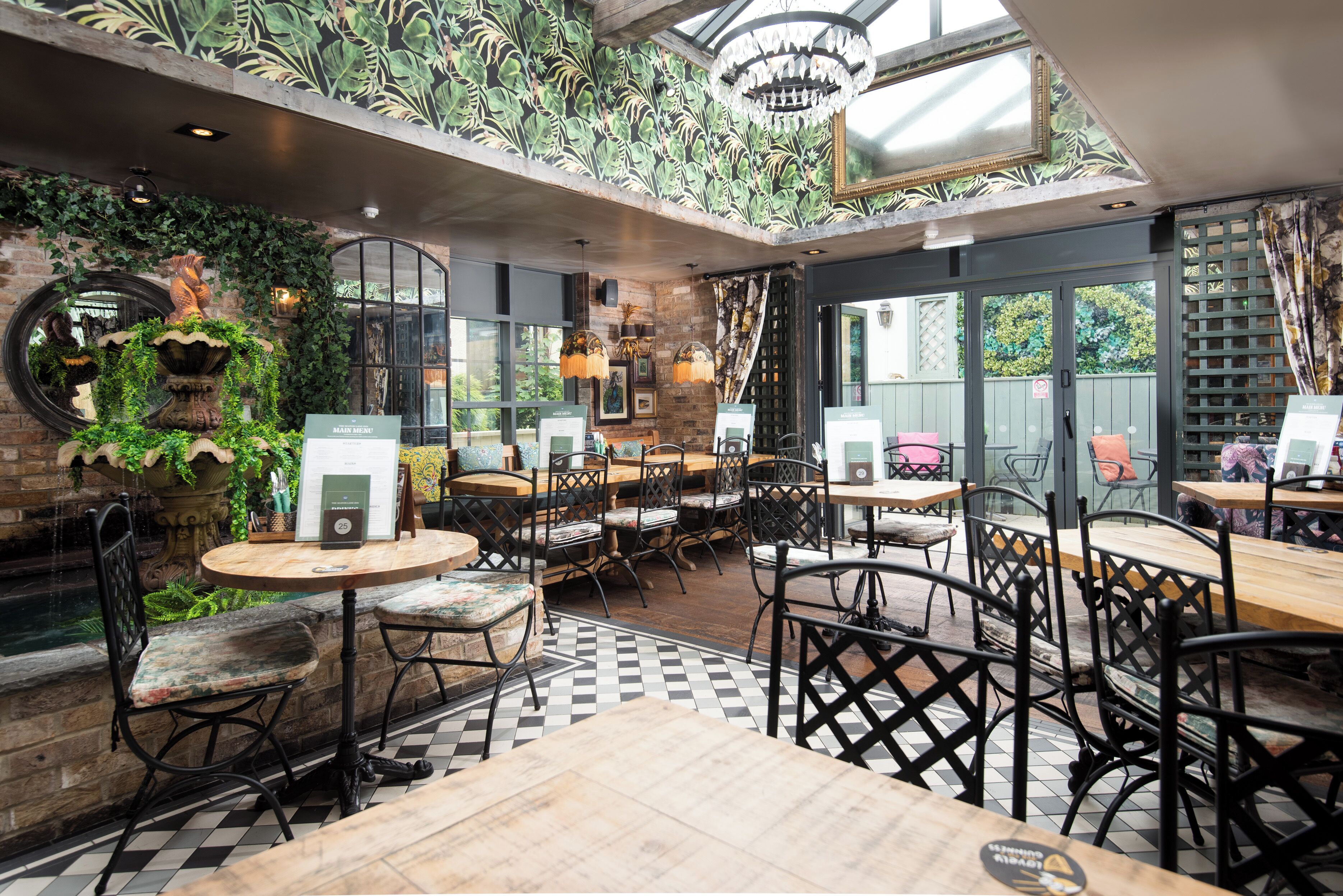A restaurant with indoor seating, a brick wall, and a ceiling garden.