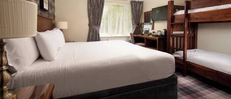 A hotel room with a large bed, a desk, a computer, and a bunk bed.