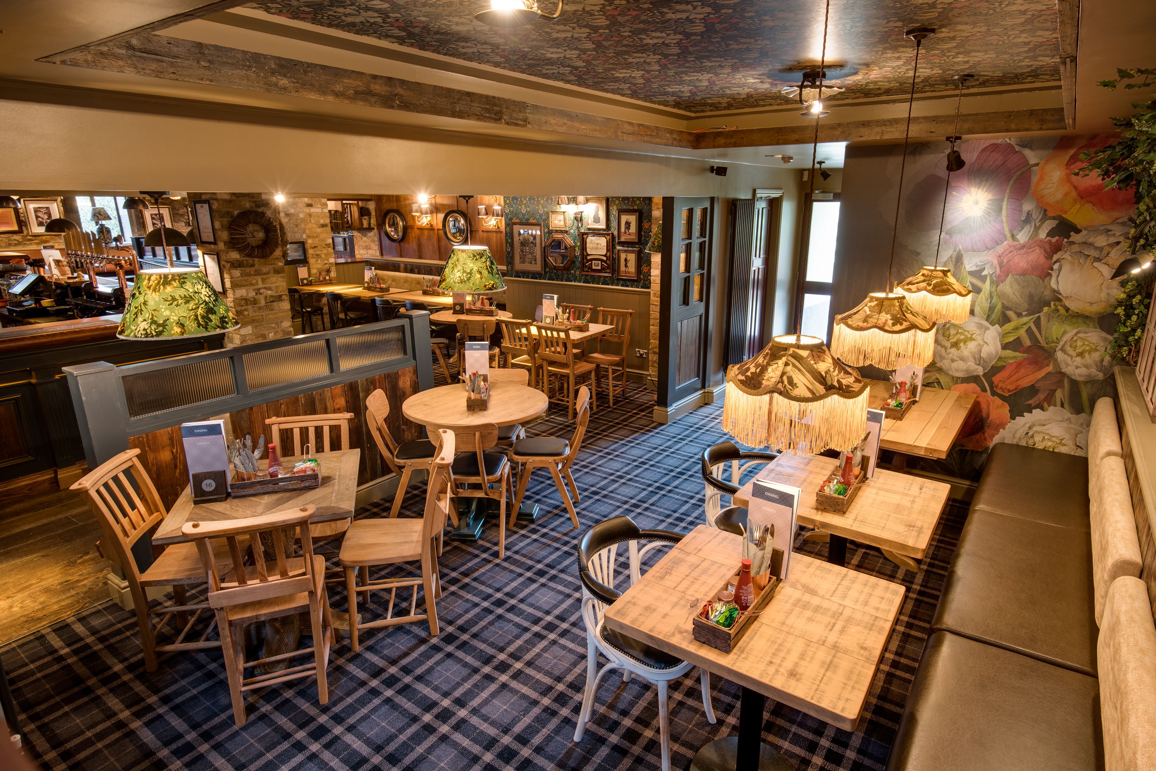 A restaurant with wooden furniture, a checkered floor, and a mural of flowers on the wall.