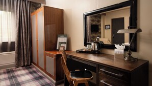 Une chambre d’hôtel avec un bureau en bois, une chaise, un miroir, une lampe et un comptoir d’enregistrement.